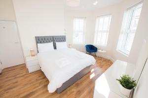 a white bedroom with a large bed and a blue chair at Space Apartments - One Bed Seafront Apartment 4 in Harwich