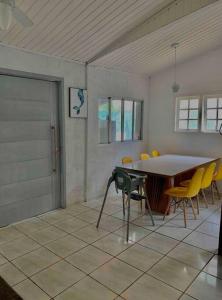 a dining room with a table and yellow chairs at Casa de Praia com piscina in São Sebastião