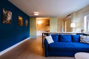 sala de estar con sofá azul y cocina en The Zentral Suites & Apartments, en Sevilla