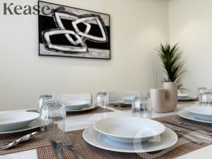 uma mesa de jantar com pratos brancos e talheres em Kease Al Izdihar -7 Luxury Gold AZ99 em Riyadh