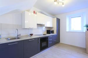 eine Küche mit weißen Schränken und einer Spüle in der Unterkunft Holiday home Šenta in Ljubač