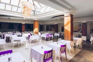 un comedor con mesas blancas y sillas moradas en Hotel Slovenska Plaža, en Budva