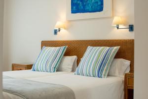 two beds with striped pillows in a hotel room at Apartamentos LIVVO Coloradamar in Playa Blanca