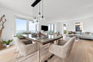 a dining room and living room with a table and chairs at Ferienwohnung Nordglanz – Modernes Beachhouse-Flair im Herzen des OstseeResort Olpenitz in Olpenitz