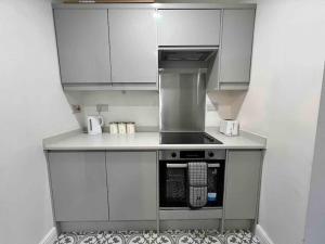 a small kitchen with a stove and white cabinets at Flaxton-Luxurious Home near NEC, BHX in Birmingham