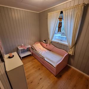 een kleine slaapkamer met een roze bed en een raam bij Koselig hus med fantastisk utsikt, Stadlandet in Stadlandet