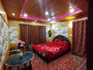 a bedroom with a red bed and a table at Sheraz Guest House Ziran Gulmarg in Gulmarg