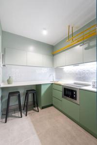 a kitchen with green and white cabinets and two stools at Estudio moderno y acogedor en Madrid Rio nº6 in Madrid