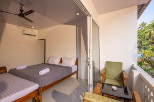 sypialnia z 2 łóżkami i krzesłem na balkonie w obiekcie Crystall Goa, Onyx Edition w mieście Palolem