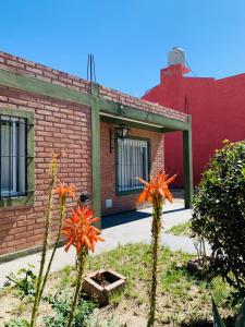 un bâtiment en briques avec des fleurs orange devant lui dans l'établissement SanVitto, à Las Grutas
