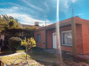 un bâtiment en briques rouges avec une porte blanche et un ciel. dans l'établissement SanVitto, à Las Grutas