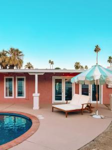 een patio met een bank en een parasol naast een zwembad bij Casita Suenito in Palm Springs