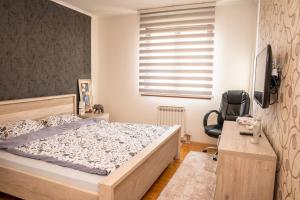 Schlafzimmer mit einem Bett, einem Schreibtisch und einem Stuhl in der Unterkunft Apartman Red Rose in Banja Luka