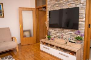 ein Wohnzimmer mit einem TV an einer Backsteinwand in der Unterkunft Apartman Red Rose in Banja Luka