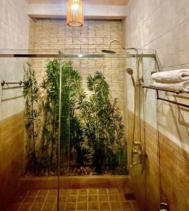 a bathroom with a shower with plants on the wall at Bungalow Sáng Tươi Mountains in Phu Quoc