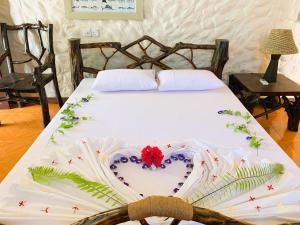Una cama blanca con una decoración de corazón. en Villa Stella, Rinbudhoo, en Dhaalu Atoll