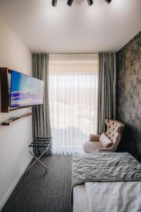 a hotel room with a bed and a flat screen tv at Garni Hotel Radović in Kragujevac