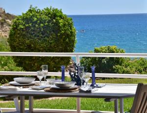 a table with plates and wine glasses on a balcony with the ocean at 1a. Línea, vistas al mar, acceso directo a playa y piscina in Salou