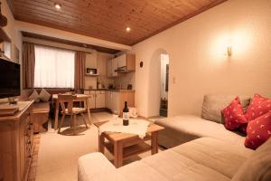 a living room with a white couch and a kitchen at Appartements Charlotte in Westendorf