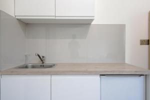 a kitchen with white cabinets and a sink at London Elegant New Studio in London