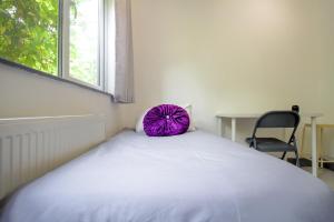 a bedroom with a large bed with a purple pillow on it at London Elegant New Studio in London