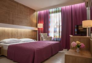 een slaapkamer met een paars bed en een televisie bij Hotel Slovenska Plaža Lux in Budva
