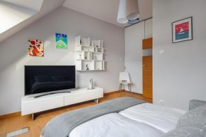um quarto branco com uma televisão e uma cama em Vasco da Gama - River View ( 2 bedroom ap + parking ) em Gdansk
