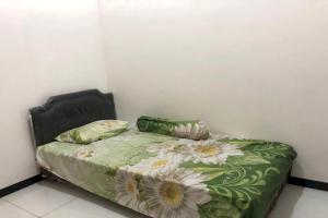 un letto con un piumone verde e fiori sopra di OYO Life 2678 Manyar Guest House a Surabaya