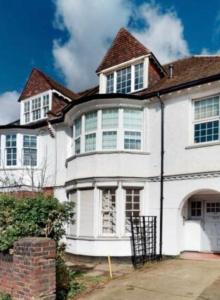 a white house with a brown roof at Spacious & Charming garden flat -Zone 2- Great for Central London access in London