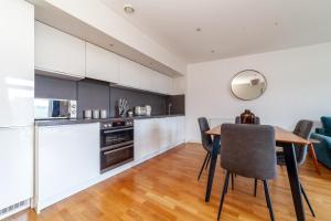 cocina y comedor con mesa de madera y sillas en The Park Royal Collection en Londres