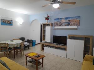 een woonkamer met een televisie en een tafel bij Sunshine Holiday Apartment 4 Next to the Sea in St Paul's Bay