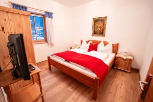 a bedroom with a bed with a red blanket and a tv at Chalet Isabella in Westendorf