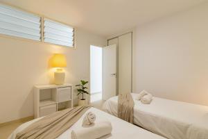 two beds in a white room with a window at HORIZON VACATION HOME - Firstline Las Burras in San Bartolomé de Tirajana