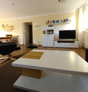 a living room with a white table and a tv at Ferienwohnung Sonne und Meer in Ulstrupfeld