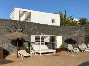 a group of chairs and umbrellas in front of a wall at Apartamentos LIVVO Coloradamar in Playa Blanca