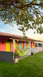 a colorful house with a hammock in front of it at Vila Cajuzinho in Caraíva