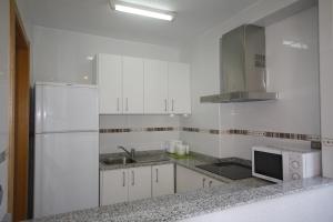a white kitchen with a sink and a refrigerator at Apartamentos Maysan in Benidorm