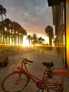 een oranje fiets geparkeerd op een stoep met palmbomen bij à 50 m des plages, proche du vieux port et hypercentre superbe 3 P moderne in Cannes