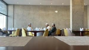 a group of men sitting at tables in a restaurant at Royal Plaza Hotel in Duqm +115 photos