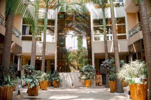 een arium van een gebouw met palmbomen en planten bij Tigers's apartment Hotel in Bujumbura