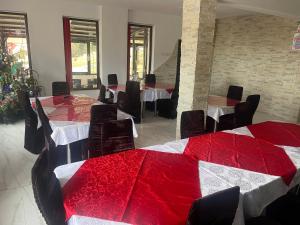 a dining room with tables and chairs with red covers at Pensiunea White House in Straja