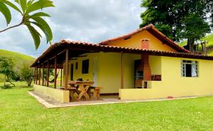 una pequeña casa amarilla con mesa de picnic en Sitio Boa Esperança 20km de Monte Verde, en Camanducaia