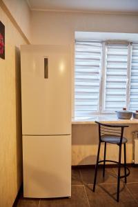 a refrigerator in a kitchen with a table and a chair at DeLuxe Ap Almaty Центр in Almaty