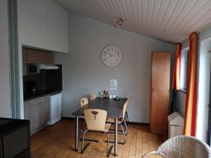a kitchen with a table and chairs and a clock on the wall at Le repaire des renards Vallée de Rabais in Virton
