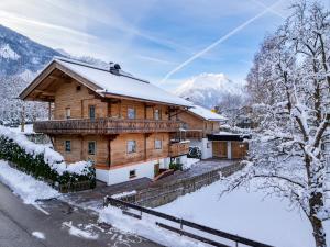 una casa de madera en la nieve con una valla en Chalet - Appartements Julitta, en Mayrhofen