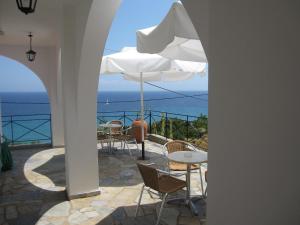 a patio with chairs and tables and an umbrella at Travlos Studios in Póros Kefalonias
