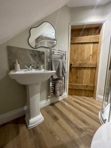 a bathroom with a sink and a mirror and a door at Roseberry Barn, Bullamoor, Northallerton, North Yorkshire in Brompton
