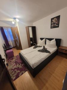 een slaapkamer met een groot bed met witte lakens bij Pensiunea White House in Straja