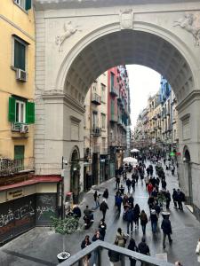 um grupo de pessoas andando por uma rua sob um arco em Ponte di chiaia em Nápoles