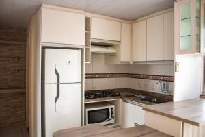 a kitchen with white cabinets and a refrigerator at Otimo apto 9 min do aeroporto em Florianopolis SC in Florianópolis
